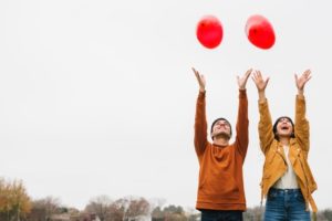 pareja-joven-juguetona-soltando-globos_23-2148215589